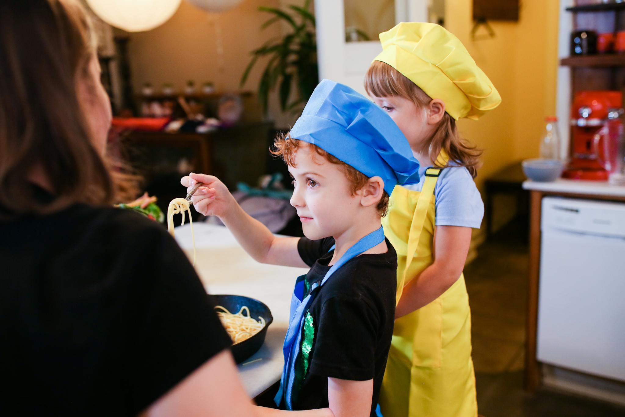 Children wearing chef hats cooking pasta in a lively kitchen setting. Inspiring young chefs.