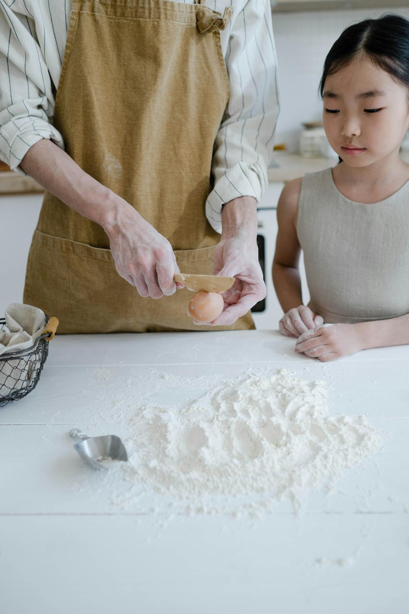 Father and daughter cracking eggs together as part of a home baking activity.