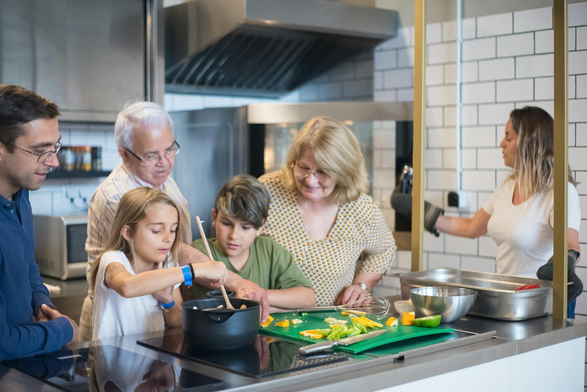 Multi-generational family enjoying cooking together in a modern kitchen setting.