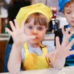 Two kids in colorful aprons enjoying a baking session, showcasing fun and togetherness.