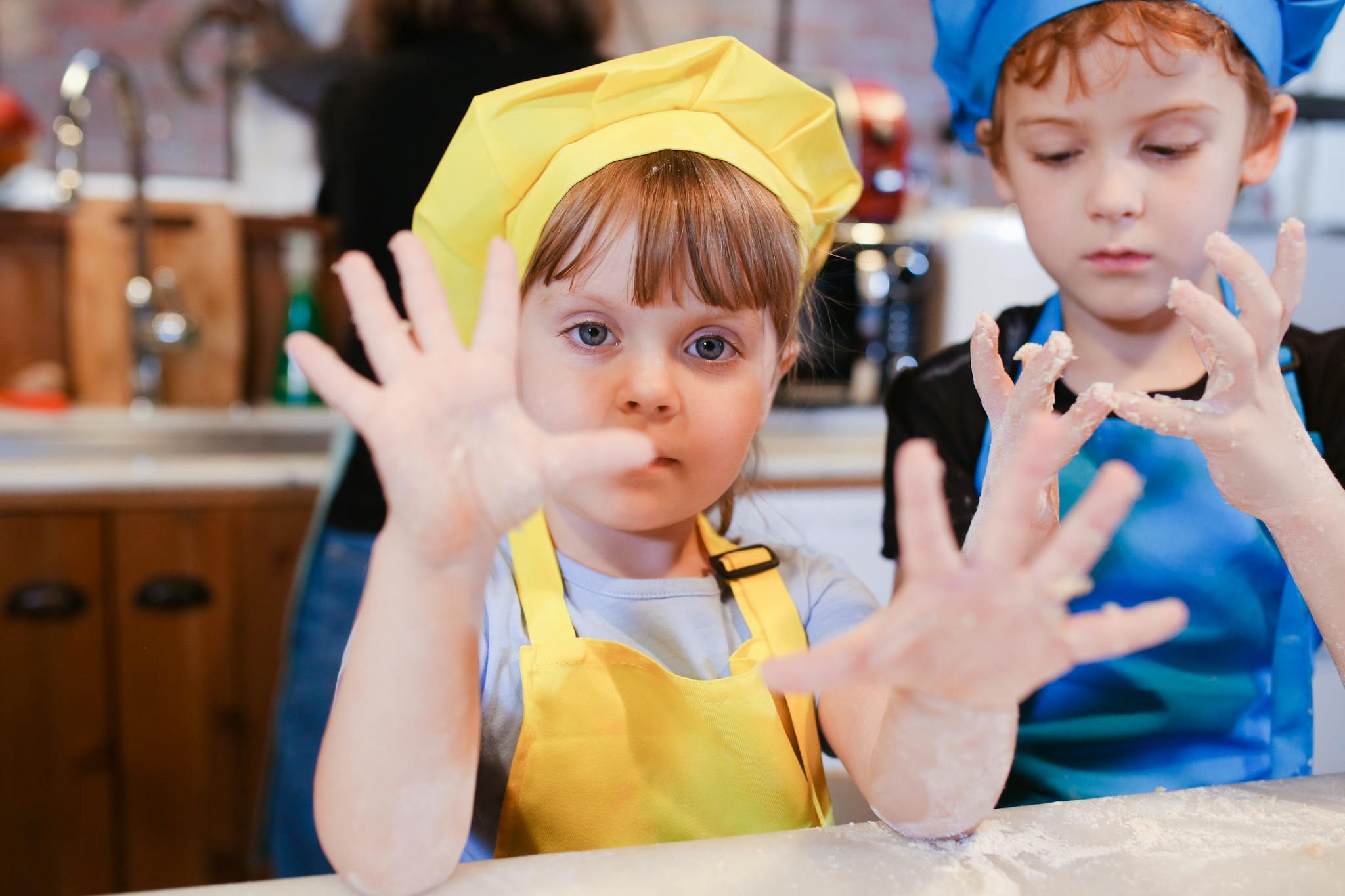 Two kids in colorful aprons enjoying a baking session, showcasing fun and togetherness.
